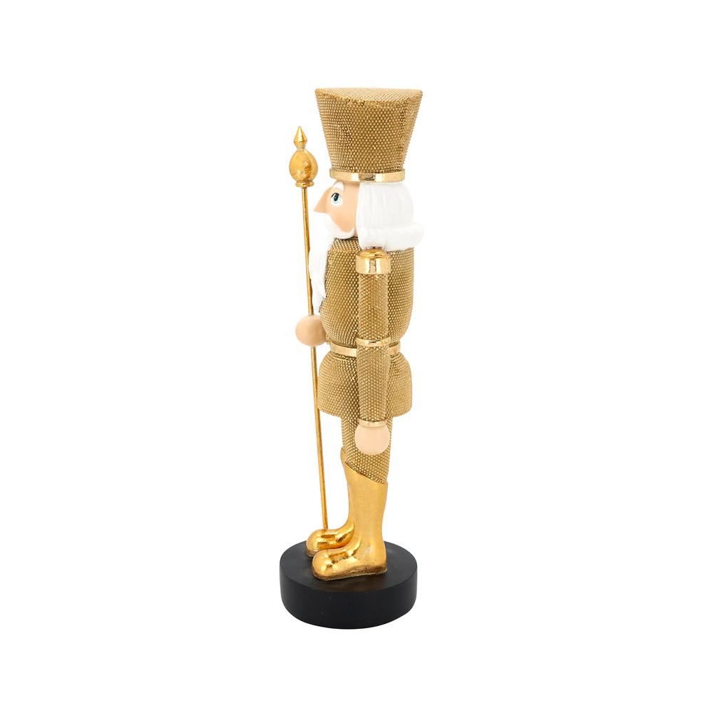 A gold-finished nutcracker figurine with a textured mesh pattern, white beard, and black circular base, holding a gold staff against a plain white background.
