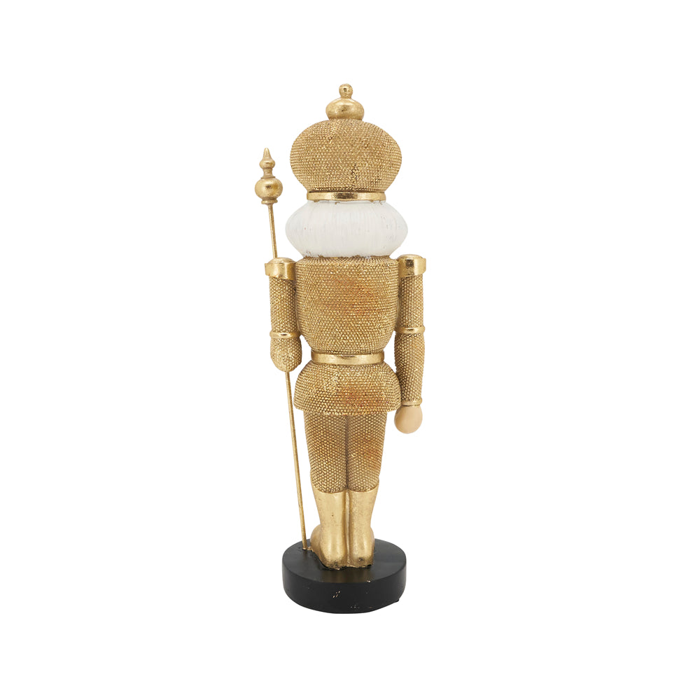 A gold nutcracker figurine with a textured metallic finish, featuring a white ruff collar, holding a gold staff, and standing on a black base against a white background.