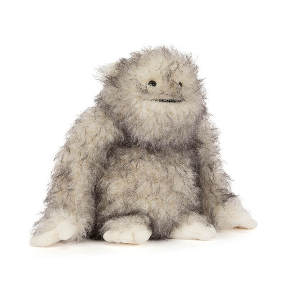 A side angeld photo of a plush toy Bretti Yeti with gray and white fur on a white background.