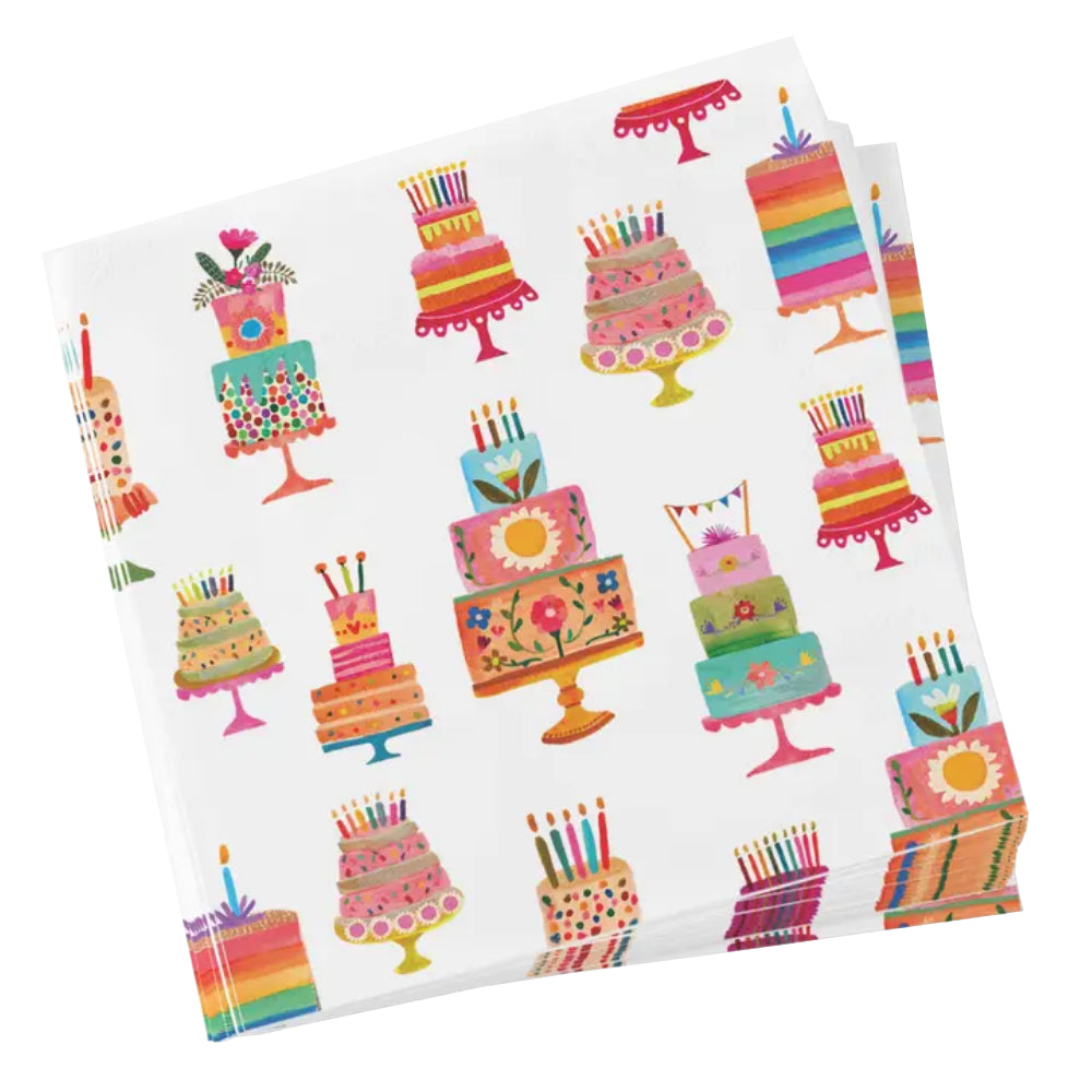 A square white stack of paper napkins featuring a colorful repeating pattern of illustrated birthday cakes on stands, photographed on a clean white background.