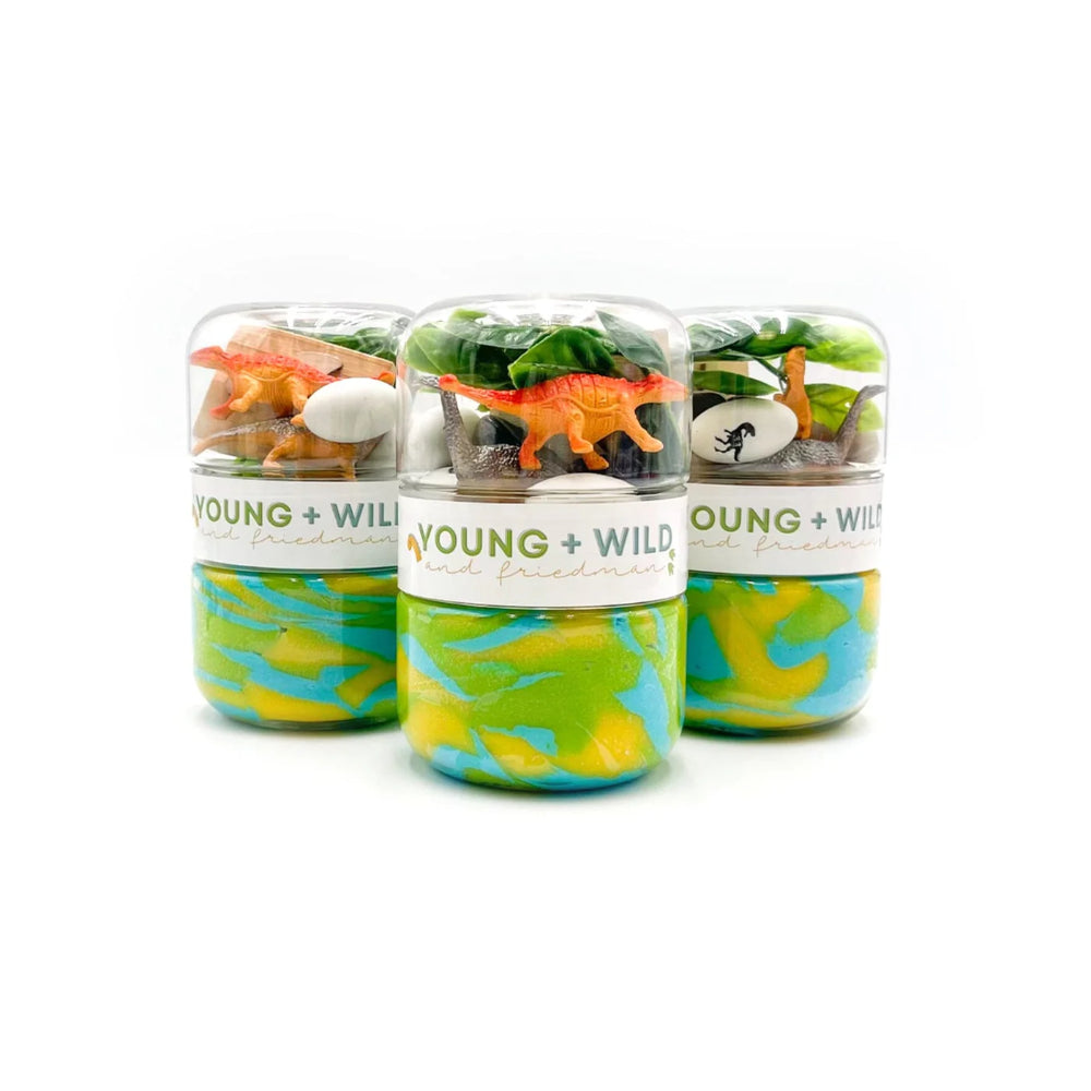Three small jars of slime with toy dinosaurs and plants labeled 'Young + Wild' on a white background.