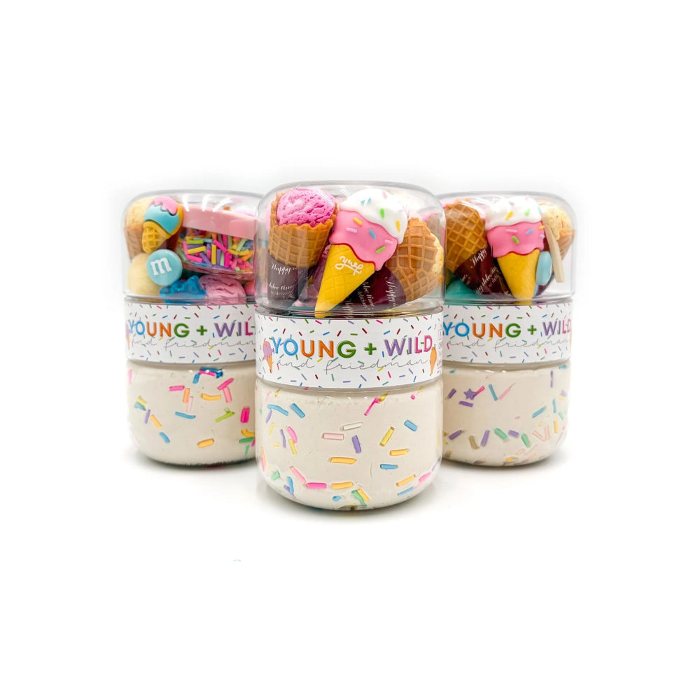 Three clear plastic jars filled with colorful toy-like treats and sprinkles, wrapped in white labels that read 'YOUNG + WILD', on a clean white background.