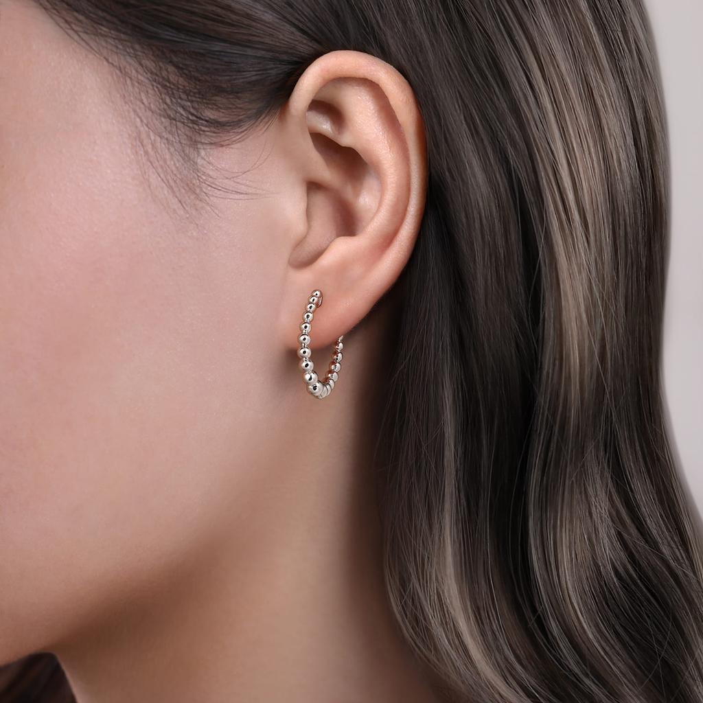 Close-up of an ear wearing a hoop earring with a neutral background