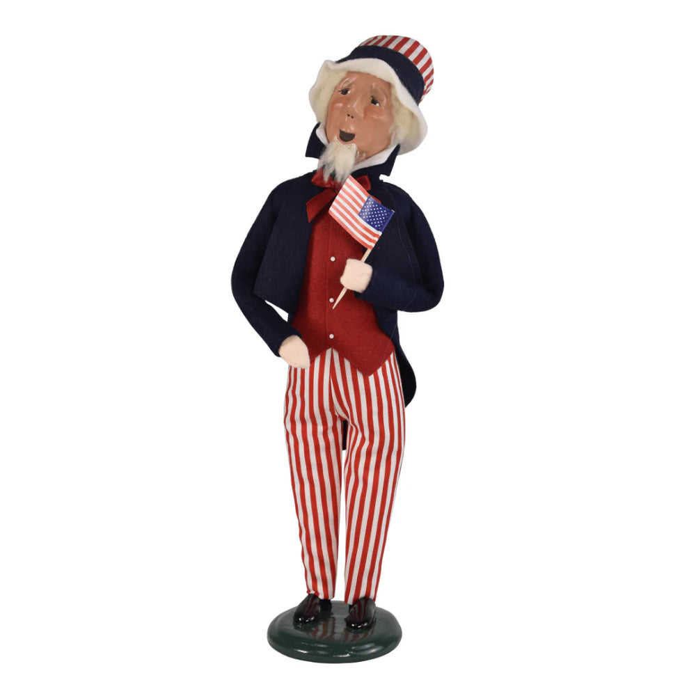 Figurine of a patriotic caroling Uncle Sam holding an American flag on a white background