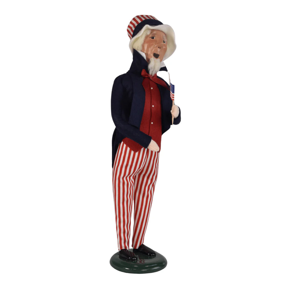 A right angled side photo of a figurine of  a caroling Uncle Sam holding an American flag on a white background