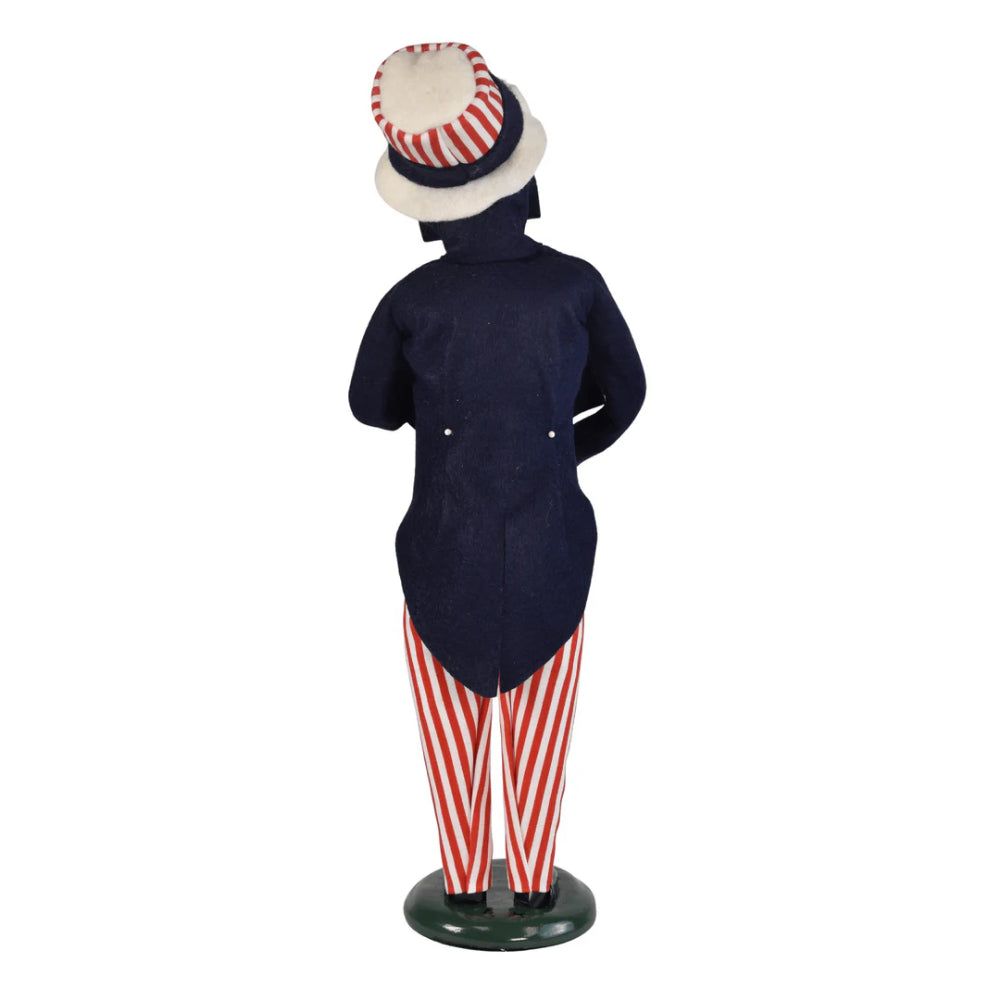 A photo of the back of a caroling Uncle Sam holding an American flag on a white background