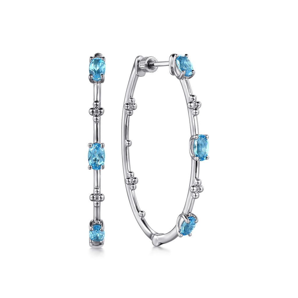 Silver hoop earrings with blue gemstones on a white background