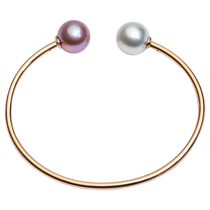 A rose gold open cuff bracelet featuring two round pearl-like beads, one with a soft pinkish-purple luster and the other with a silvery-white luster, set against a plain white background.