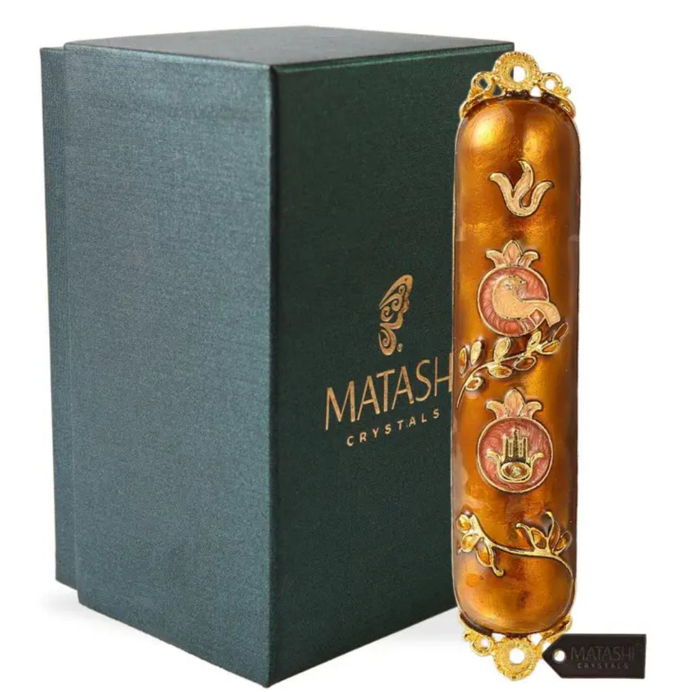 A gold-colored mezuzah with floral patterns and crystal accents, alongside a dark green box with the 'Matashi Crystals' logo.