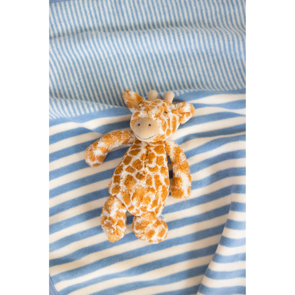 Plush giraffe toy on a blue and white striped blanket background