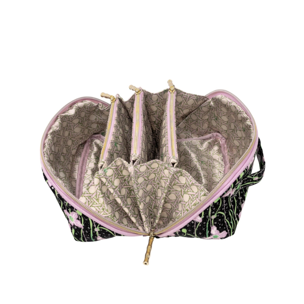 An open makeup bag with a black and pink floral exterior, a light beige patterned interior lining, and multiple zippered compartments, shown on a white background.