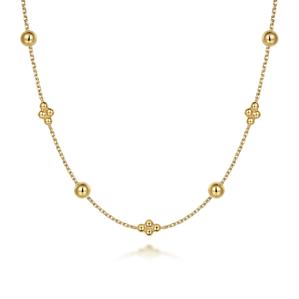 Gold necklace with spherical beads on a white background