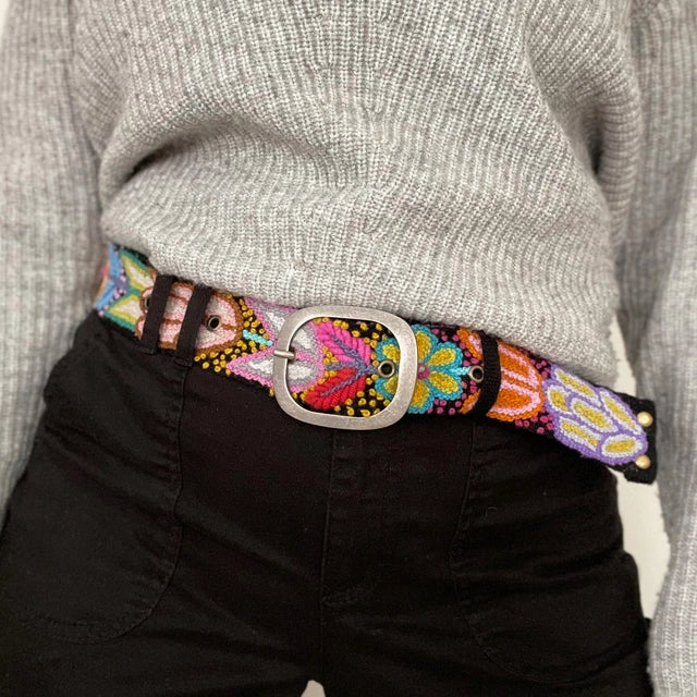 Colorful embroidered belt worn with a gray sweater and black pants