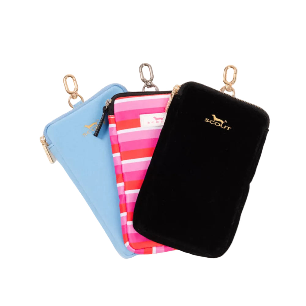 Three small zippered pouches from Scout are arranged in a fan shape on a white background. The front pouch is black velvet with gold hardware and a gold Scout logo.