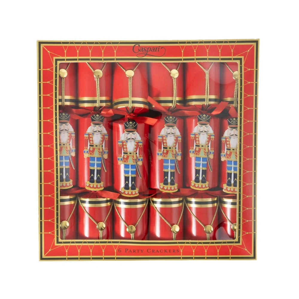 Four red Christmas cracker ornaments in a red box decorated with gold trim, gold beads, and printed nutcracker figures, tied with red ribbons on a plain white background