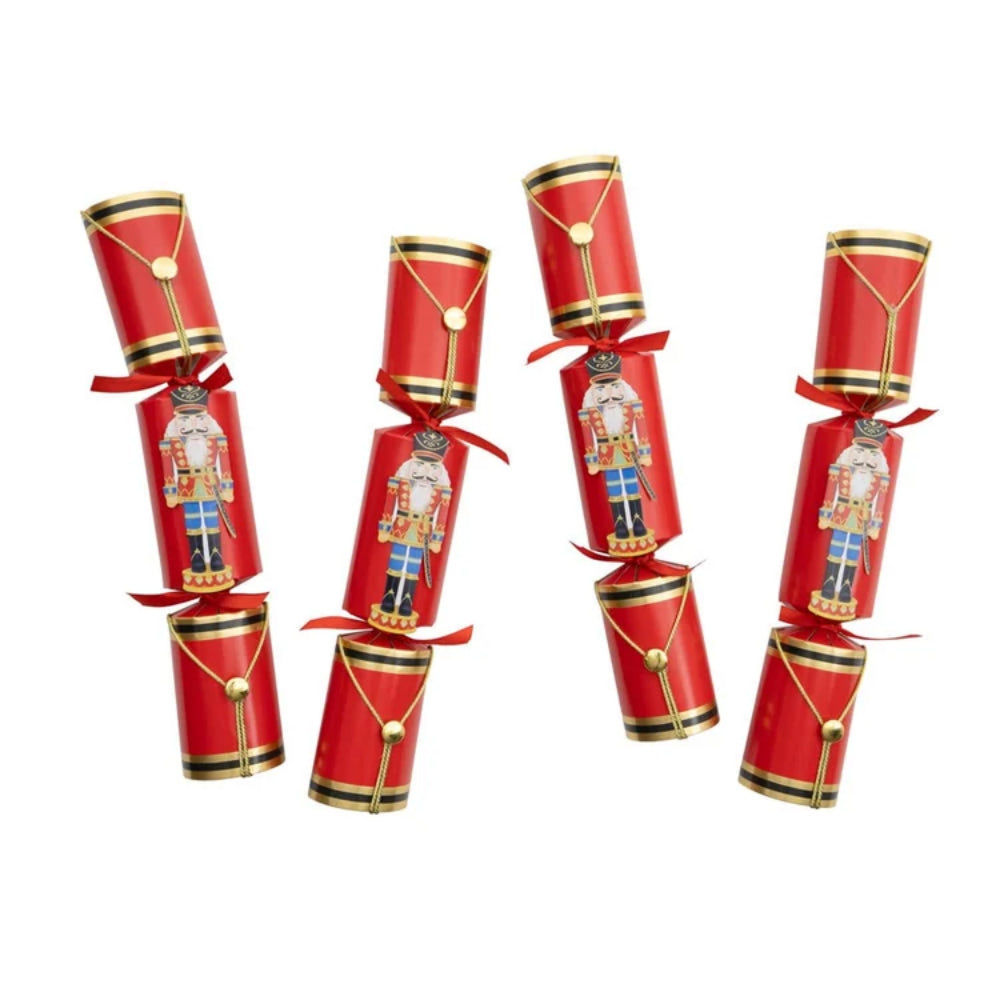 Four red Christmas cracker ornaments decorated with gold trim, gold beads, and printed nutcracker figures, tied with red ribbons on a plain white background.