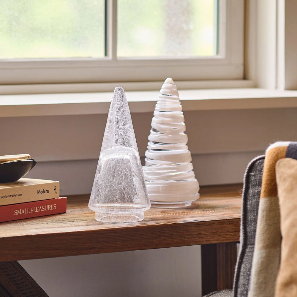 Two decorative trees on a wooden surface with a window in the background