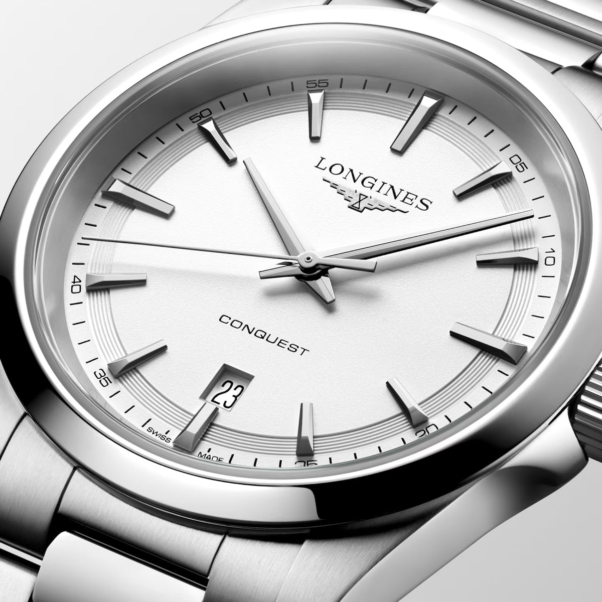 Close-up of a Longines Conquest watch with a silver stainless steel case, white dial, and silver hour markers.
