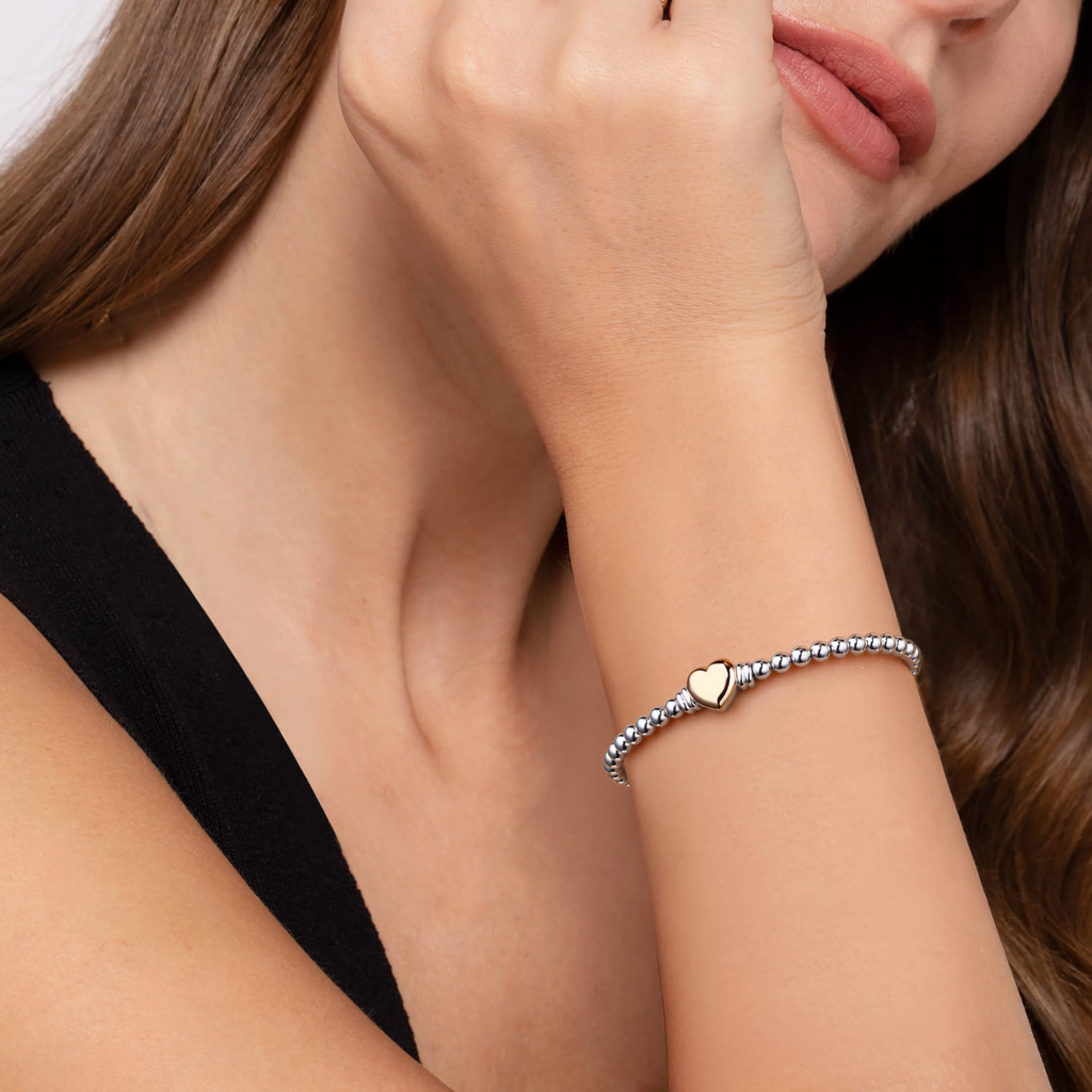 Close-up of a woman's arm wearing a bracelet with a heart charm.