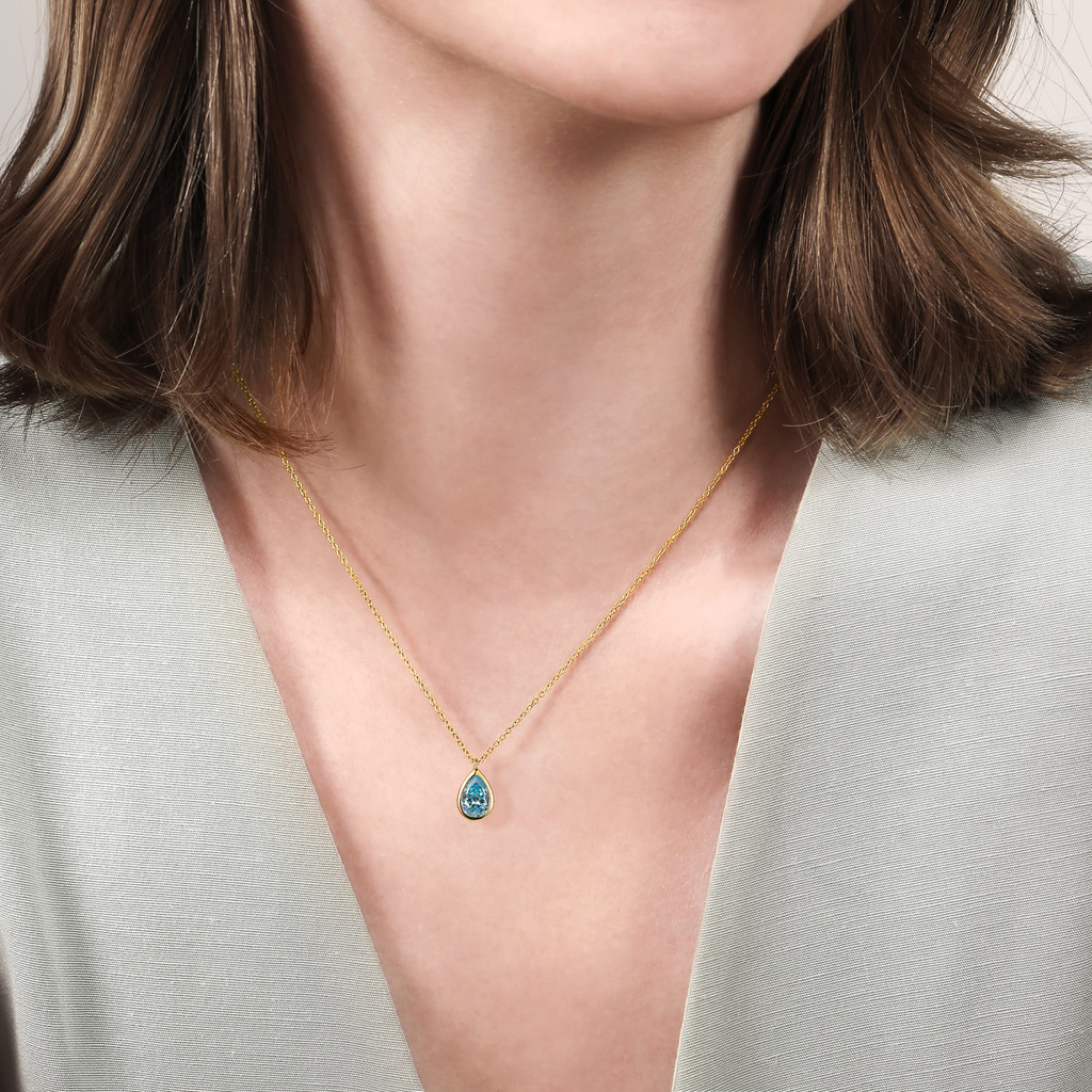 girl wearing gold necklace with blue stone center on natural background