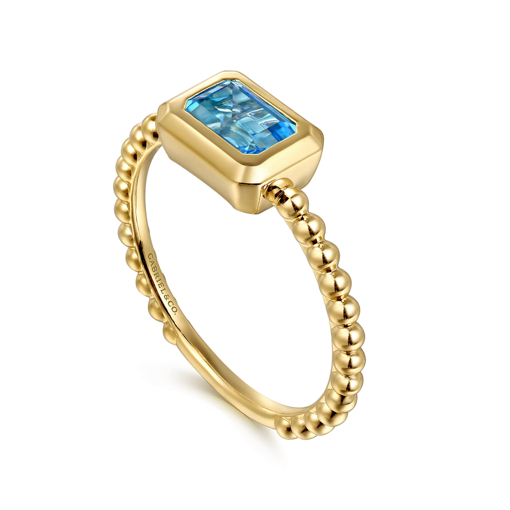 Gold ring with a blue gemstone on a white background