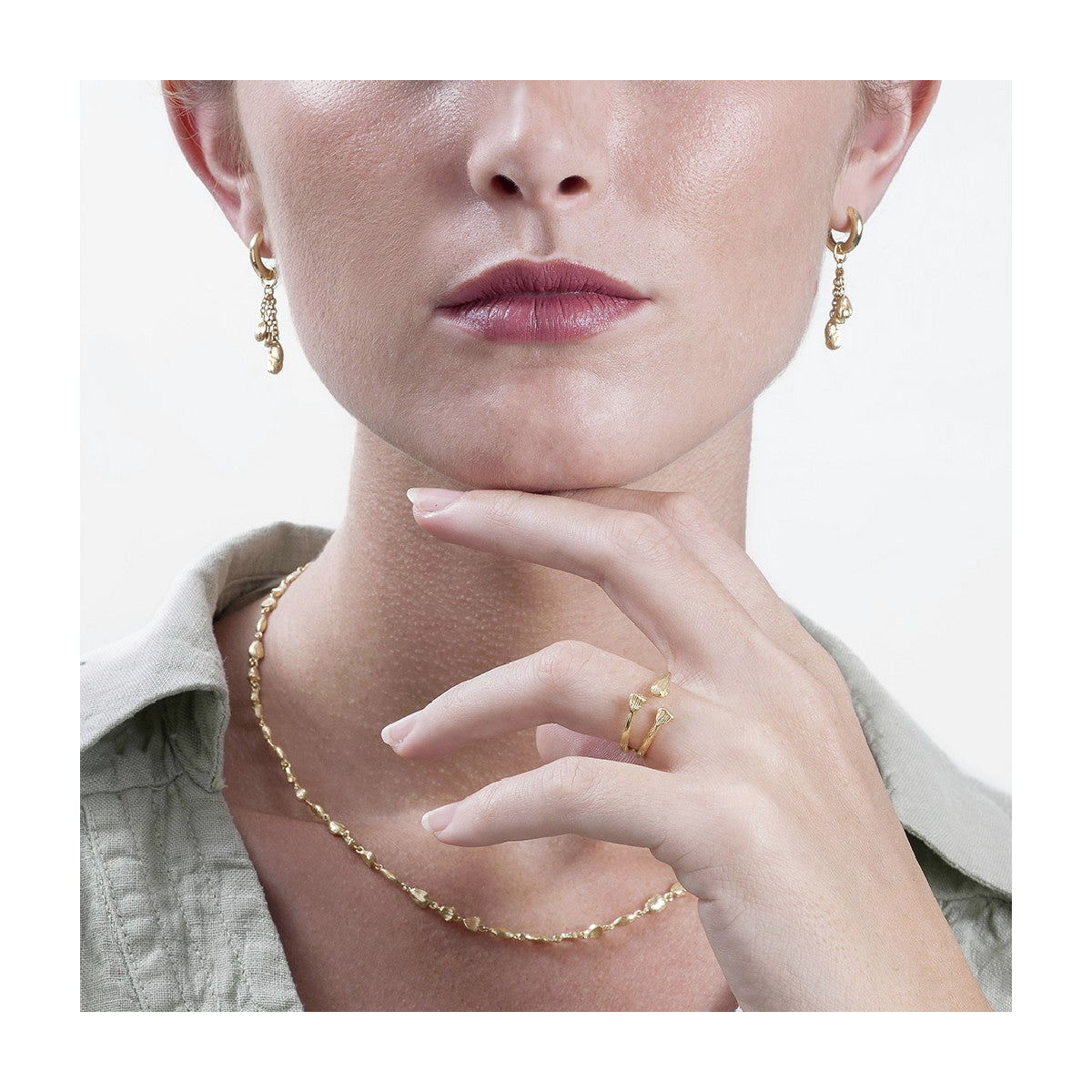 model wearing gold earrings, ring and necklace on a natural background