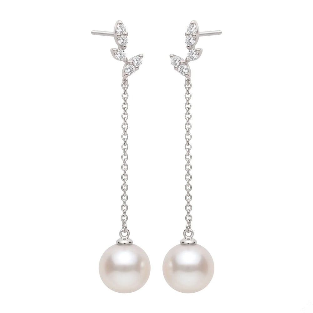 A pair of silver drop earrings featuring a small cluster of clear stones at the top, a delicate chain dangle, and a large round white pearl at the bottom, shown against a plain white background.