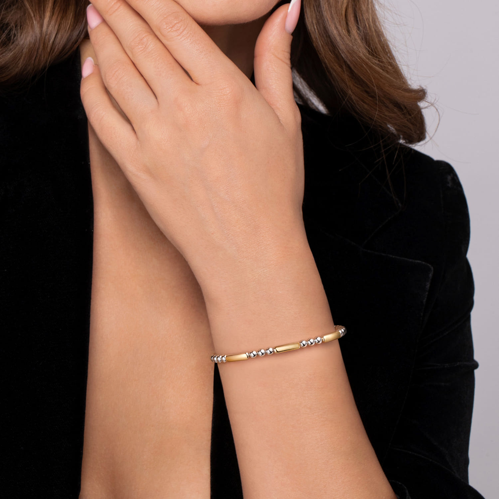 Gold bracelet on a person's wrist with a neutral background