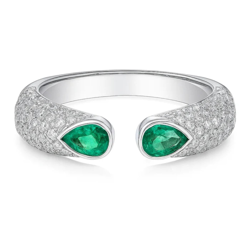 A silver-tone open cuff ring featuring two teardrop-shaped green emerald-cut center stones, with the band encrusted with pavé diamonds on a clean white background.
