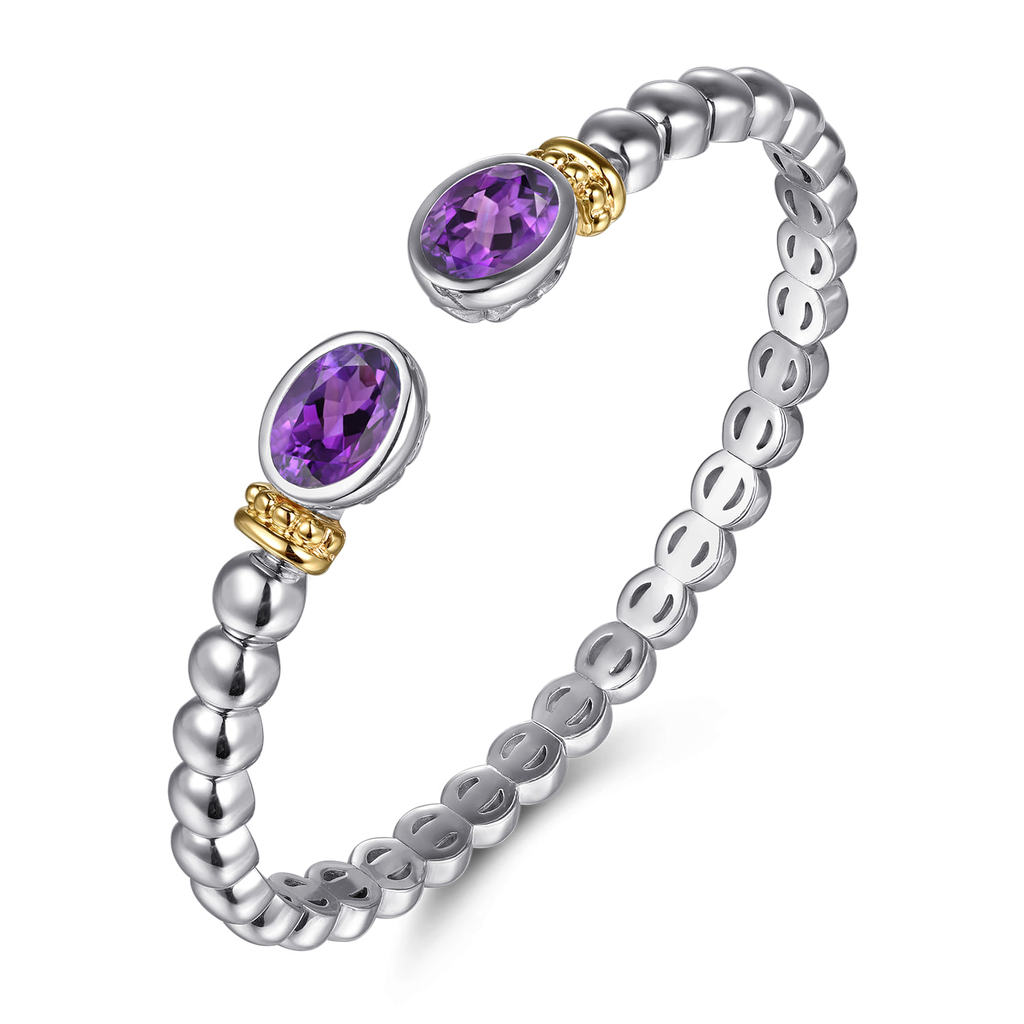Silver and gold ring with purple gemstones on a white background