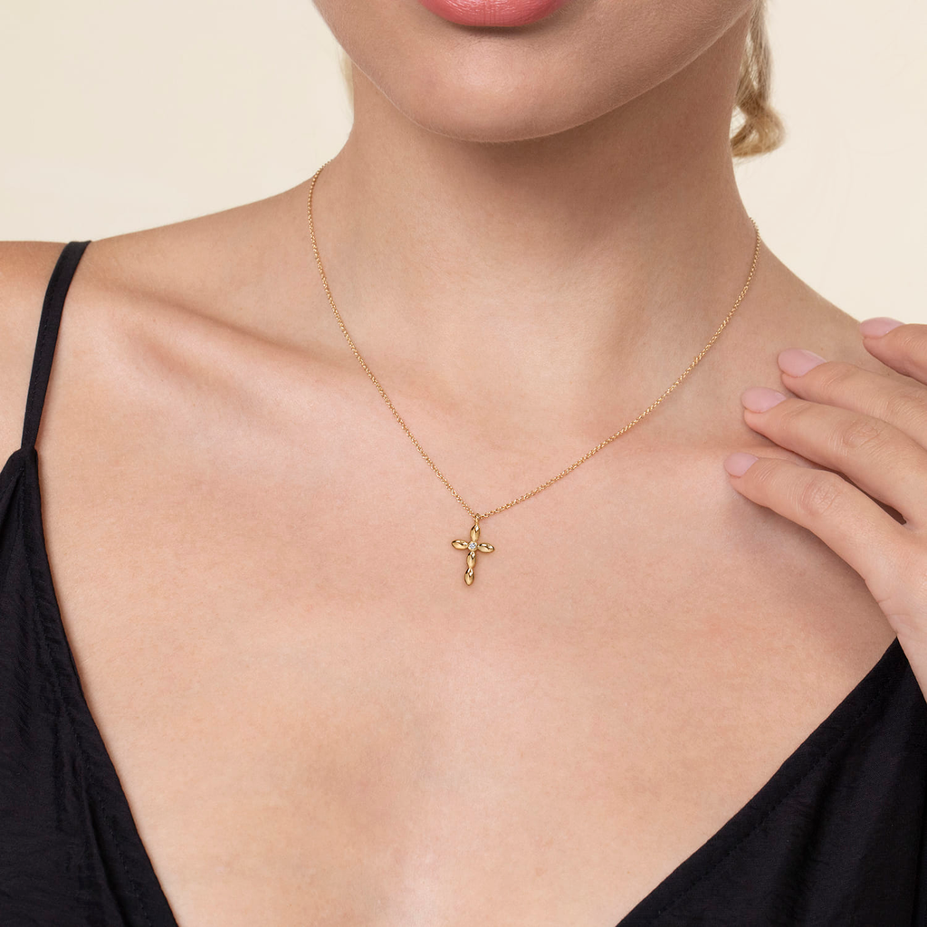 girl wearing gold cross necklace on natural background