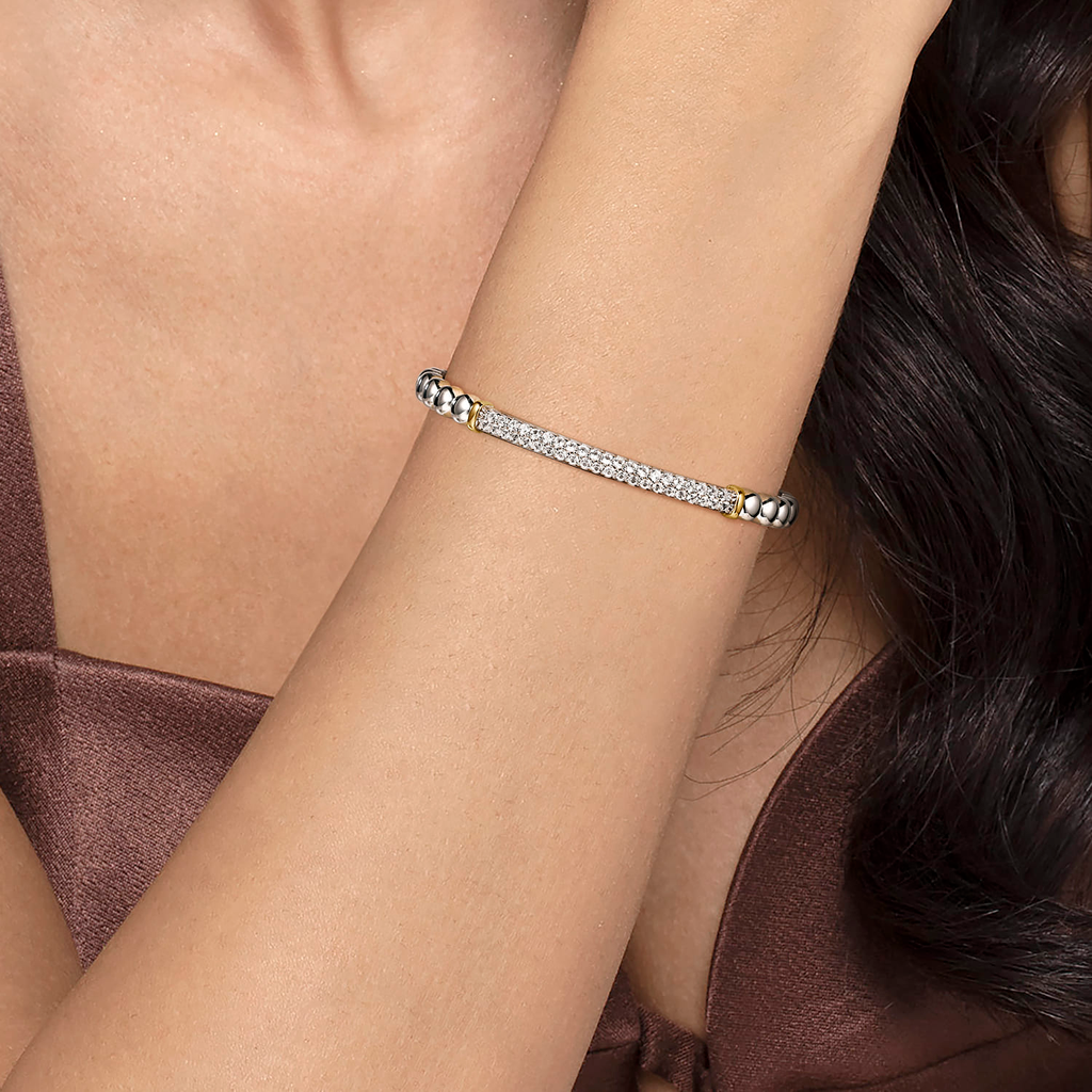 Silver bracelet on a person's wrist with a neutral background