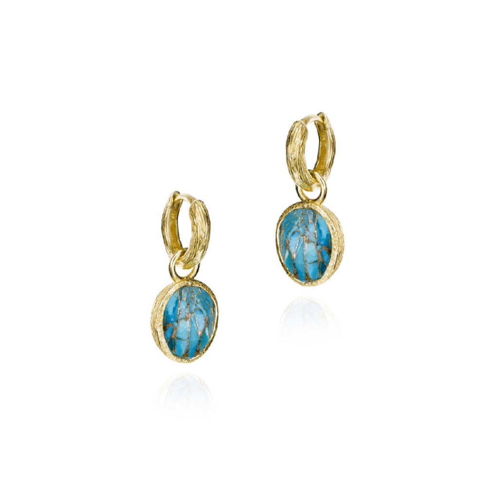 A pair of gold huggie hoop earrings with oval turquoise-blue stone drops, displayed on a clean white background with a soft reflection below.