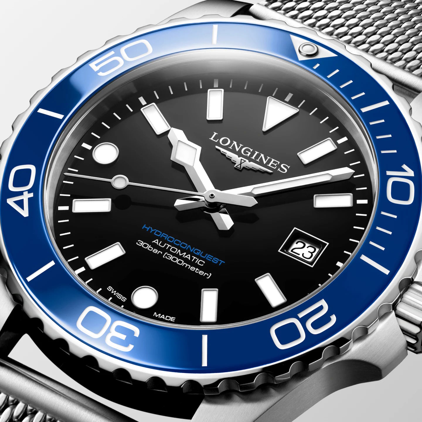 Close-up of a Longines HydroGustav Automatic 300m watch with a black dial, blue bezel, and silver stainless steel mesh bracelet.