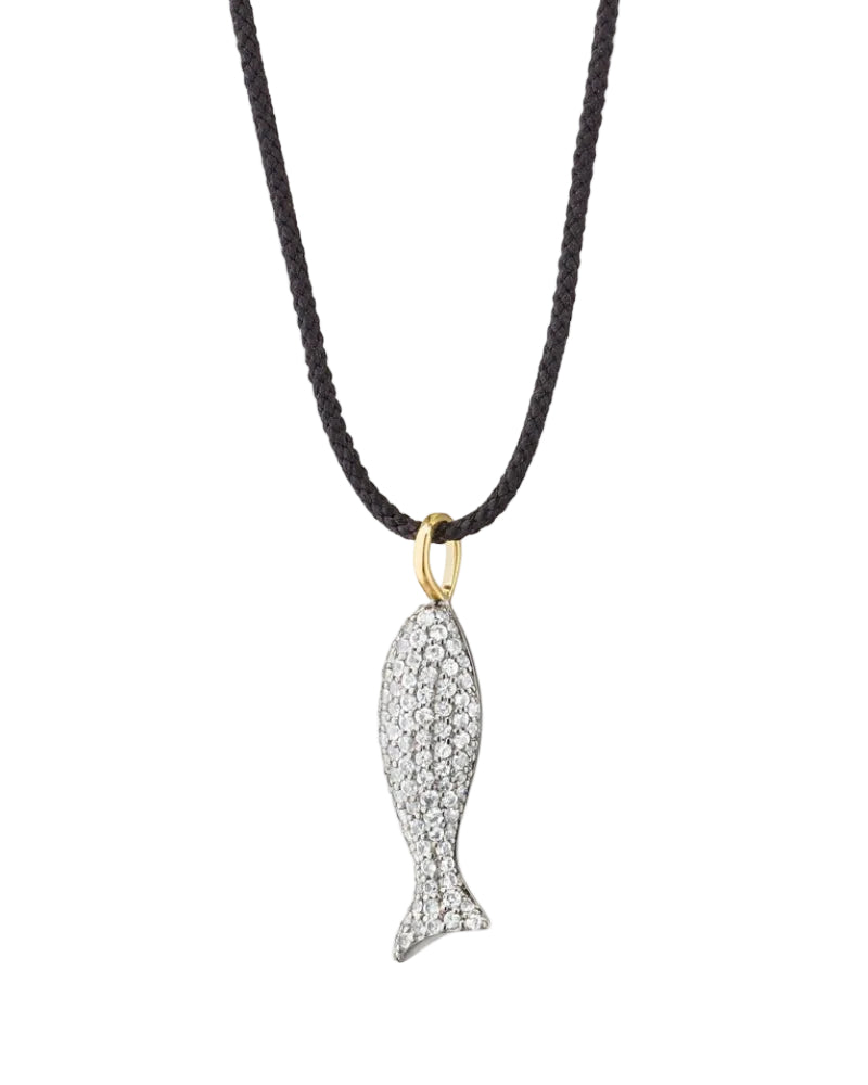 A fish-shaped pendant necklace paved with small clear stones on a black braided cord, with a gold bail, shown against a light cream background.