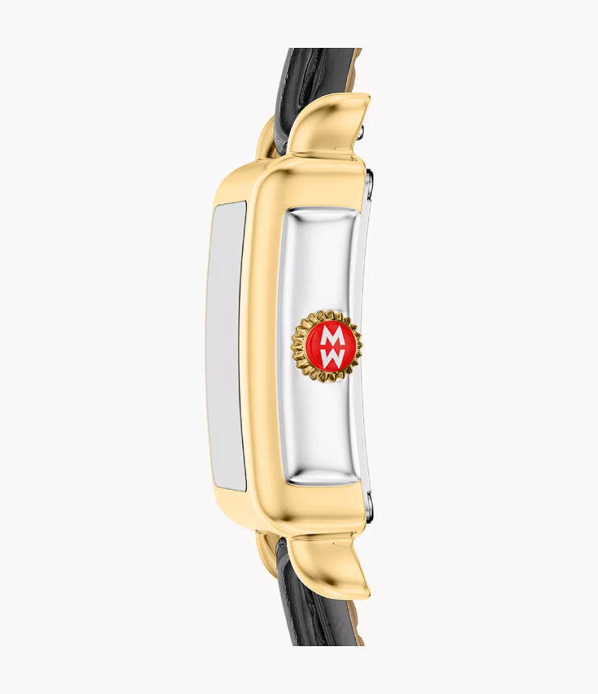 A close-up side view of a gold-toned watch case with a black leather strap, featuring a circular red and gold 'MW' logo on the side.