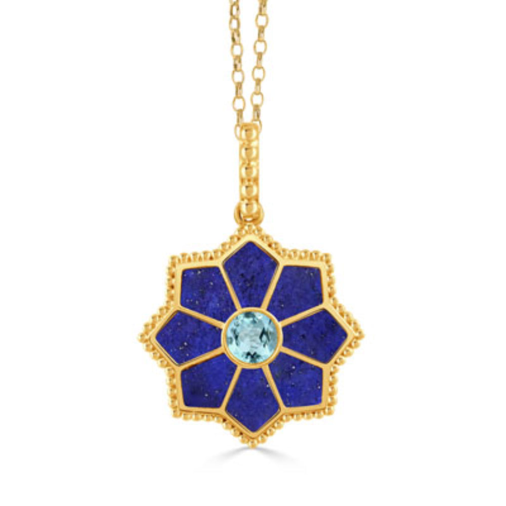 A gold pendant necklace featuring a flower-shaped design with deep blue lapis lazuli sections, a textured gold border, and a central light blue round gemstone, shown on a white background.