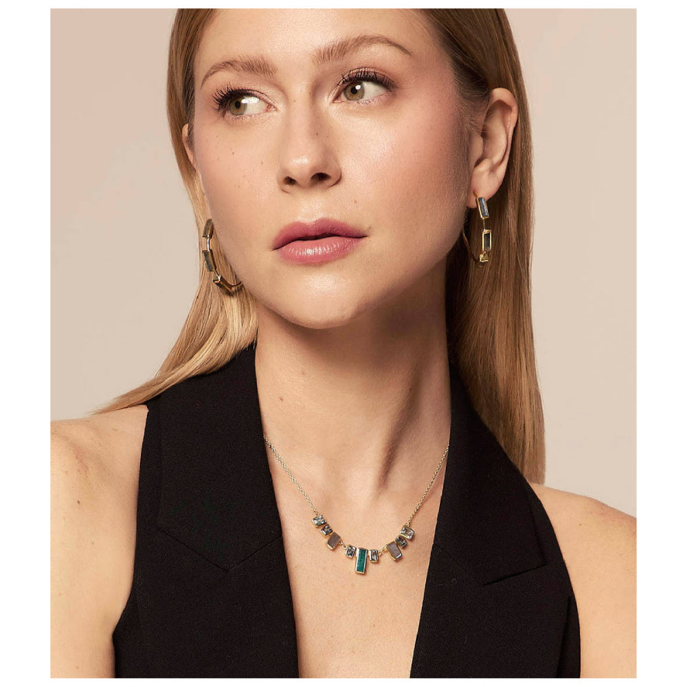 model wearing gold-tone necklace with various shades of blue stones on a natural background