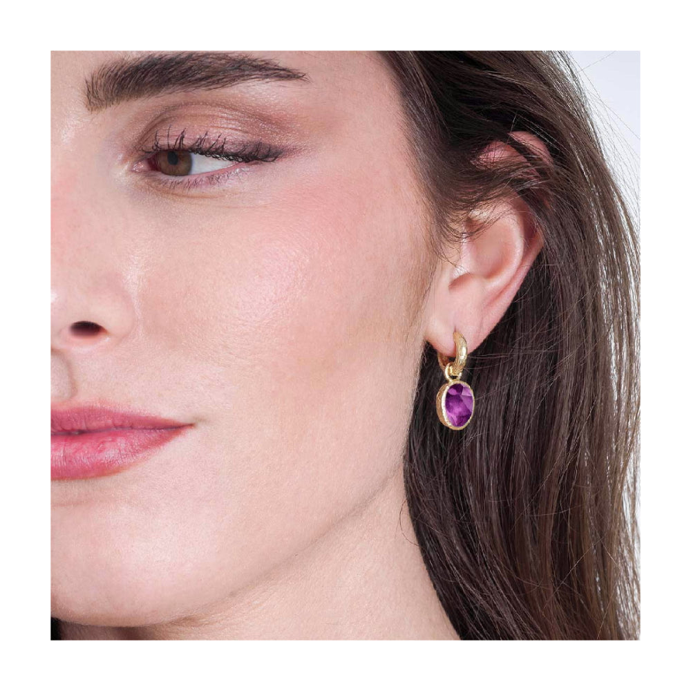 model wearing gold-tone drop earrings with purple stones on a white background