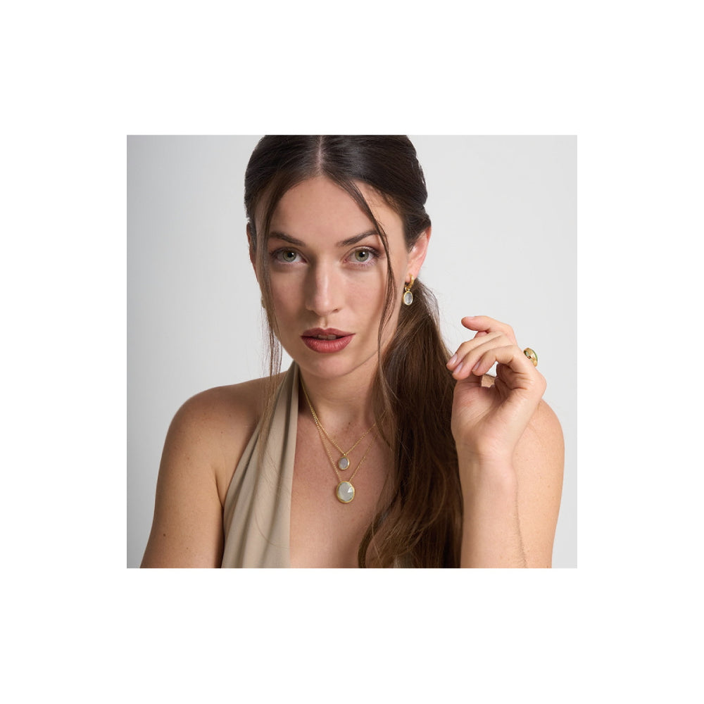 model wearing gold-tone necklace with white stone center on a natural background