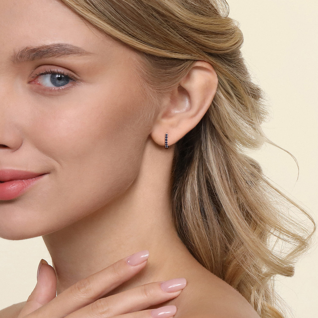 girl wearing white gold hoop earrings with blue stones on natural background