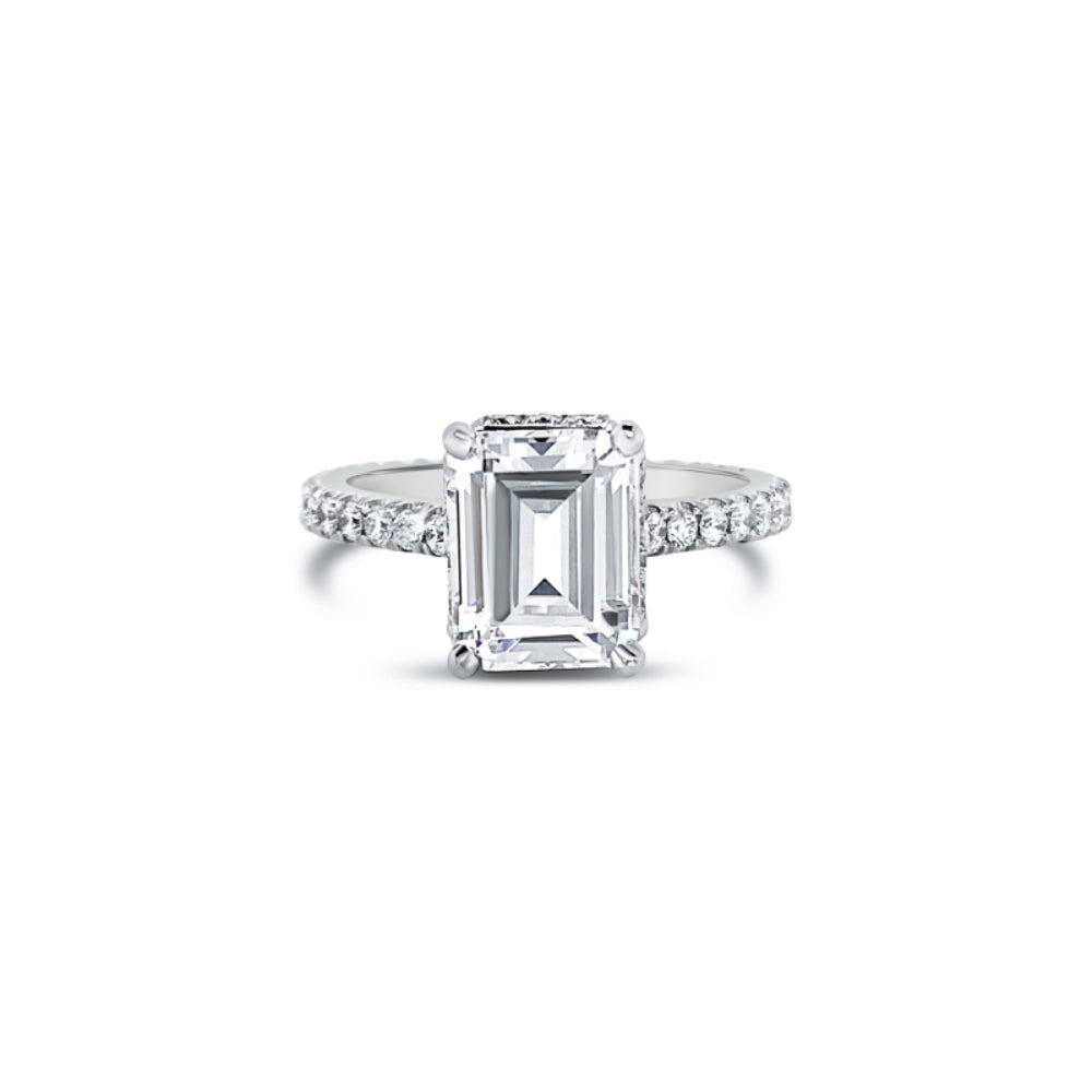 White gold diamond engagement ring with diamond accents and an emerald cut cubic zirconia center on a white background
