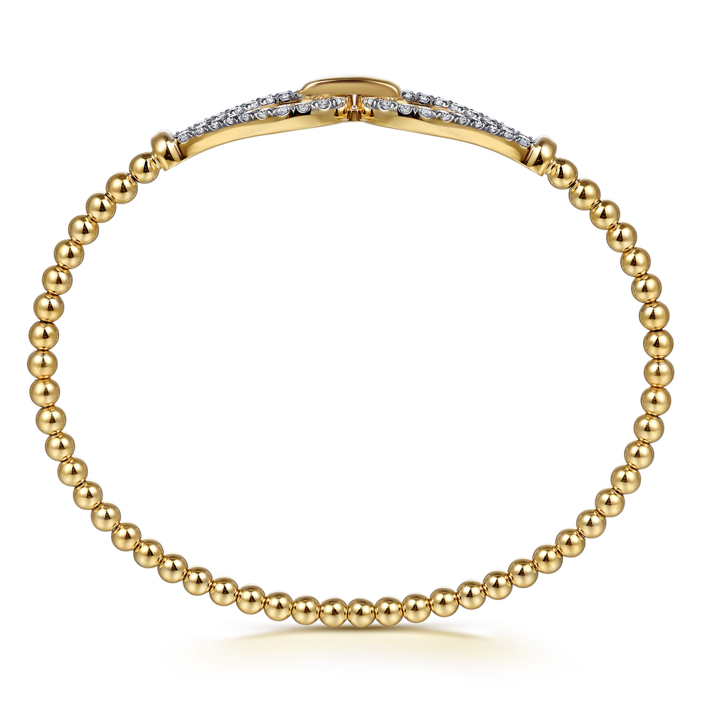 gold beaded stirrup bangle bracelet with clear stones on white background from side
