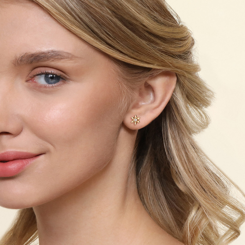 Close-up of a woman wearing gold star-shaped earrings with a neutral background