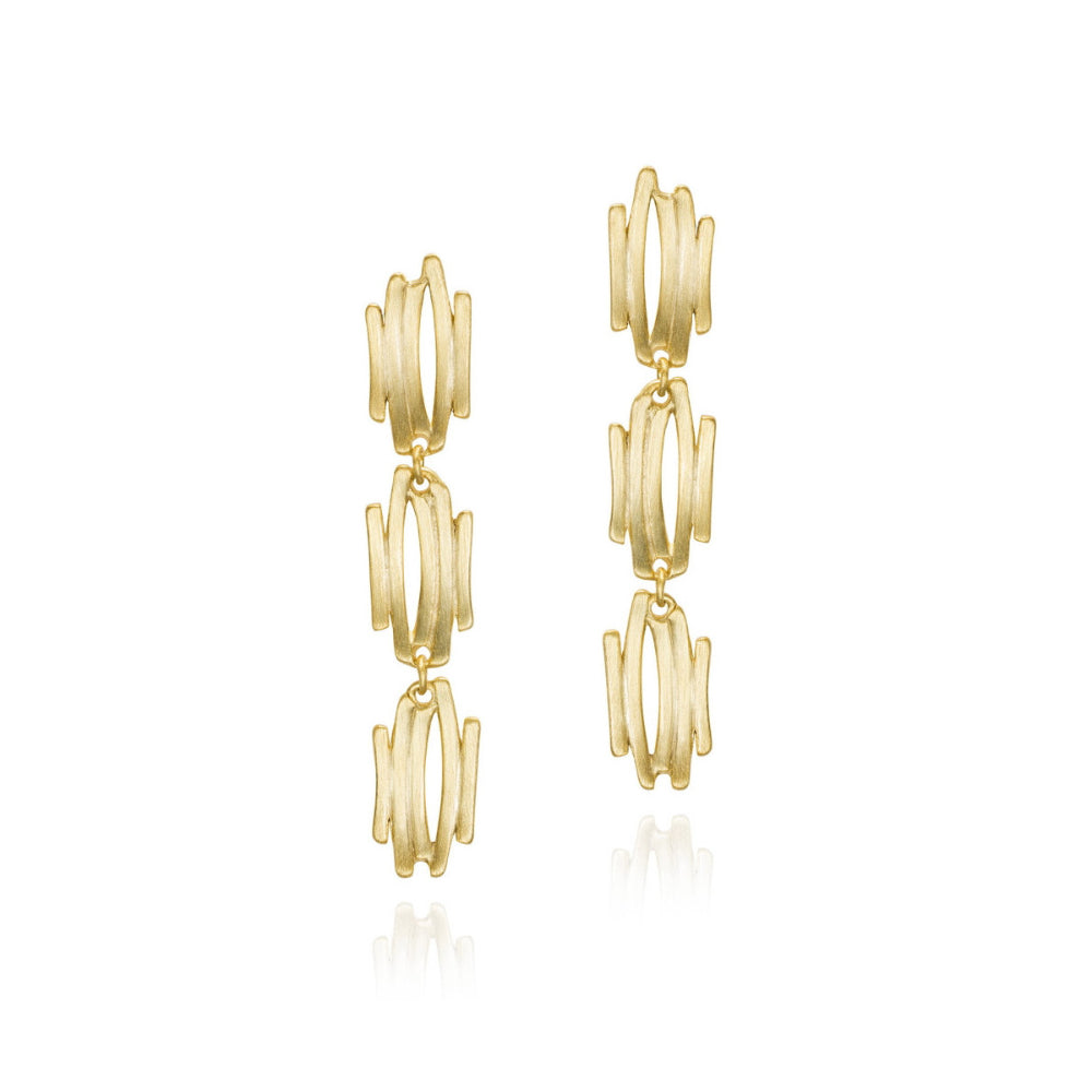 A pair of gold drop earrings with a stacked, wavy geometric design, shown on a clean white background with a soft reflection below.