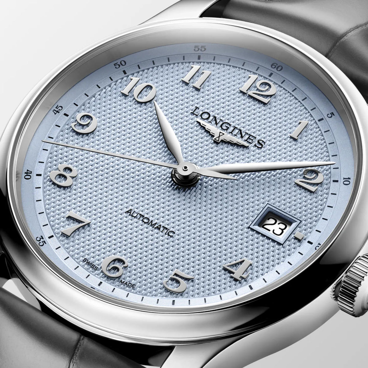 Close-up of a Longines Automatic watch with a textured light blue dial, silver-tone case, and dark gray leather strap.