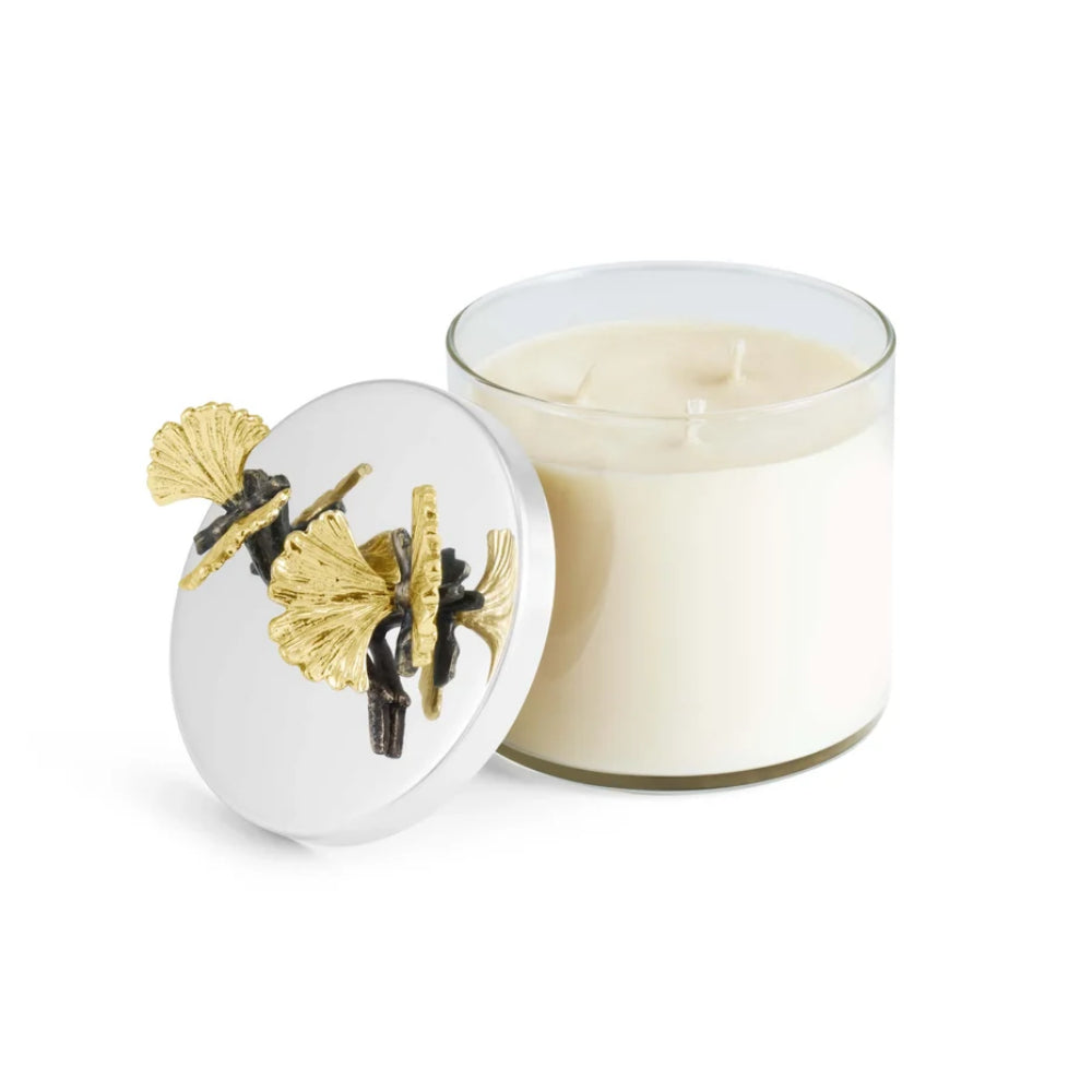 Candle in a glass jar with decorative lid featuring gold and black elements on a white background