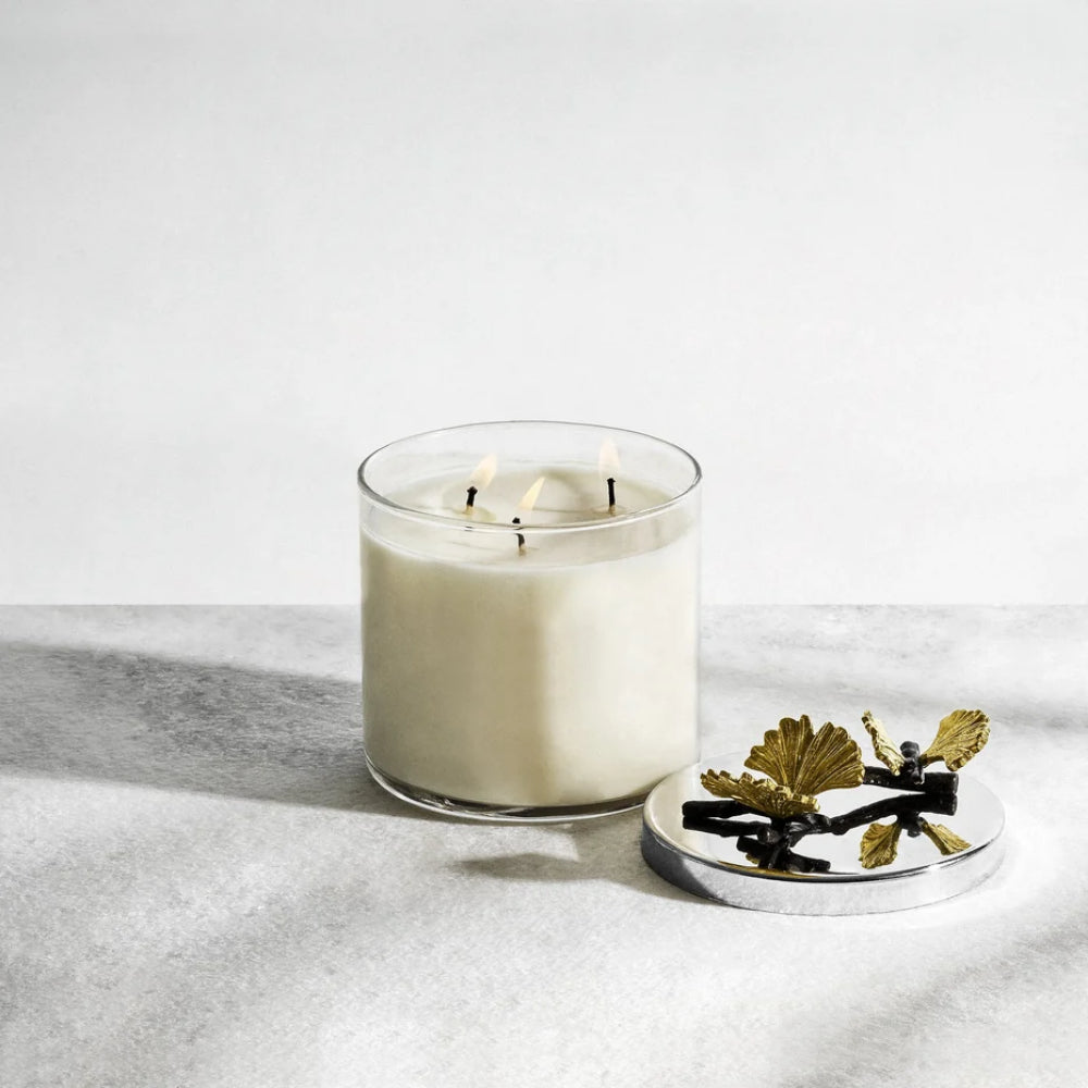 White candle in a glass jar with a decorative lid on a light gray surface