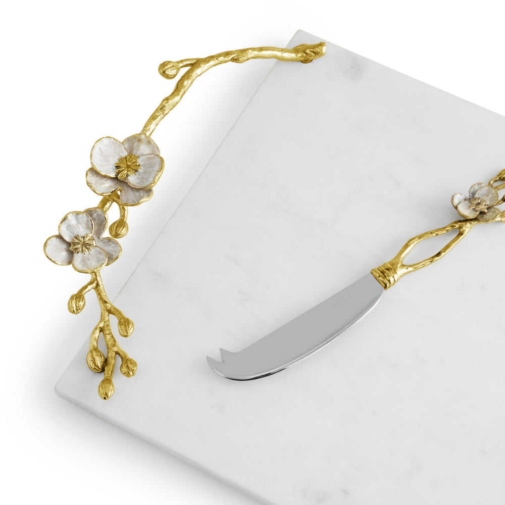 A white marble cheese board with gold Orchid detailing and a matching knife.