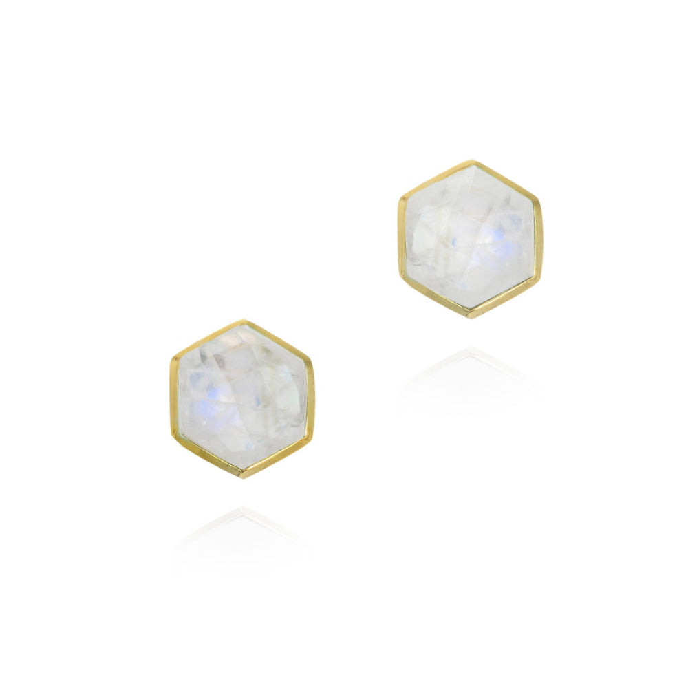 A pair of hexagonal stud earrings featuring white moonstone centers set in gold-tone metal, shown on a clean white background with a soft reflection.
